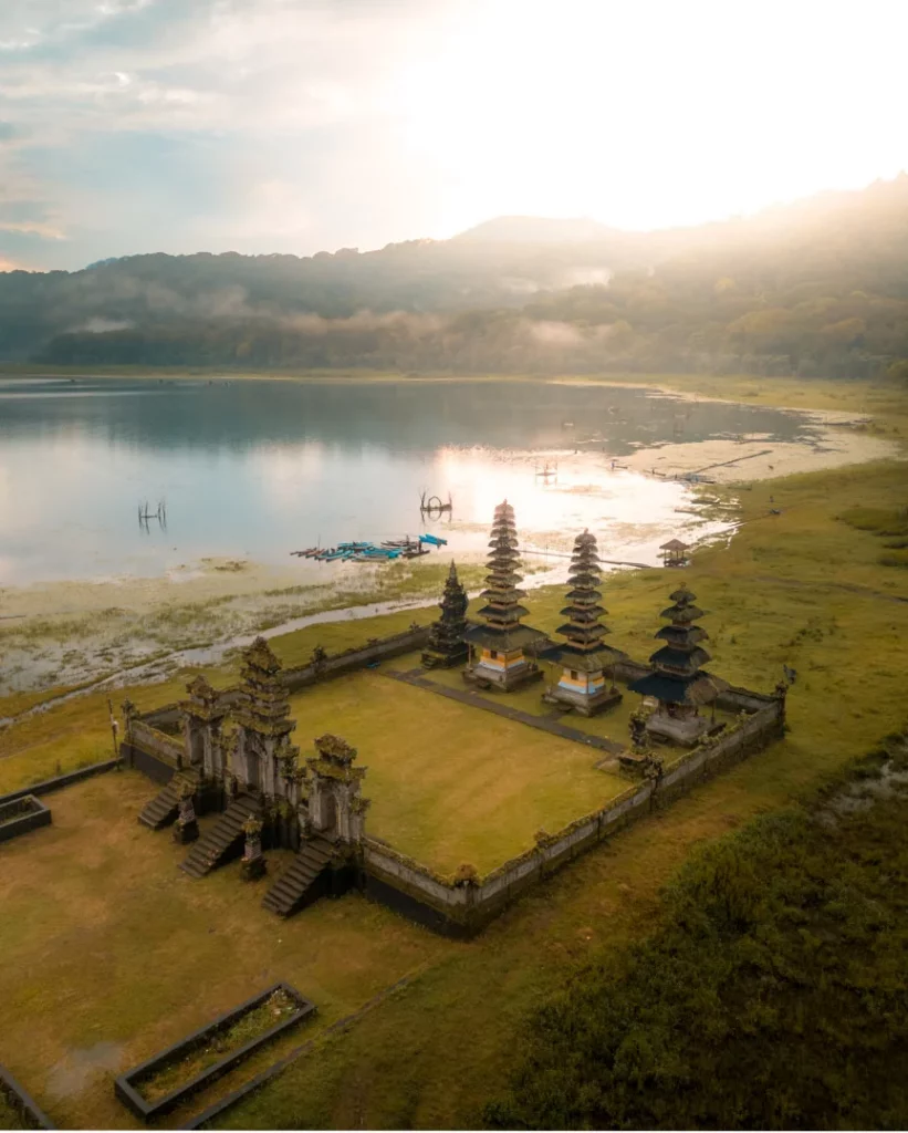 Pura Ulun Danu Bratan Temple at sunrise with a mirror-like water reflection.