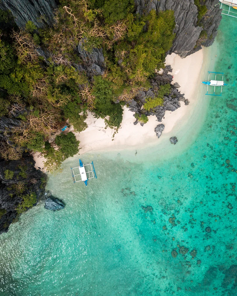 Tourists on a boat exploring the crystal-clear waters of El Nido, Philippines.