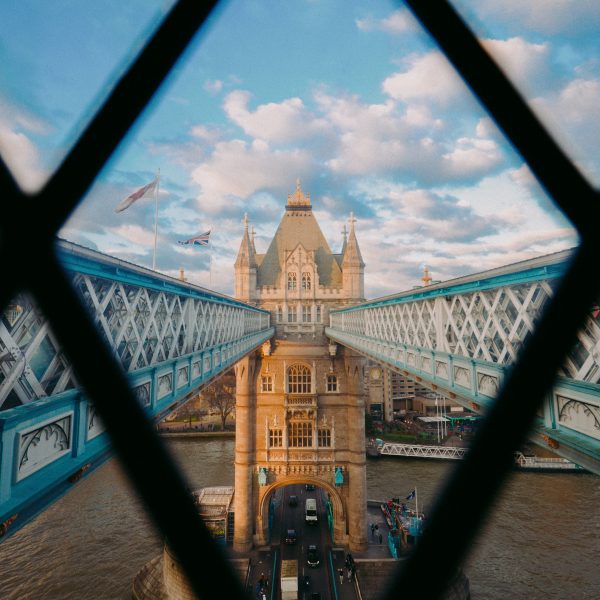 Historic image of Tower Bridge with its neo-Gothic towers and bascules raised for a passing ship.