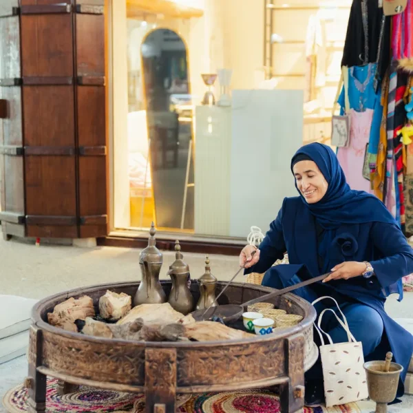 Emirati woman roasting coffee beans over hot coals in the souk, Heart of Sharjah
