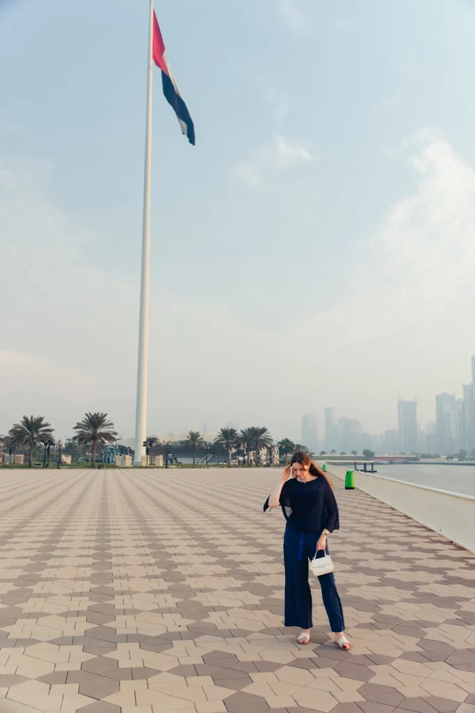 Helena walking on the patterned promenade beneath the giant UAE flag on Flag Island, Sharjah