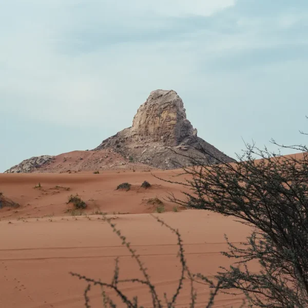 Fossil Rock rising above the red dunes of the Mleiha desert