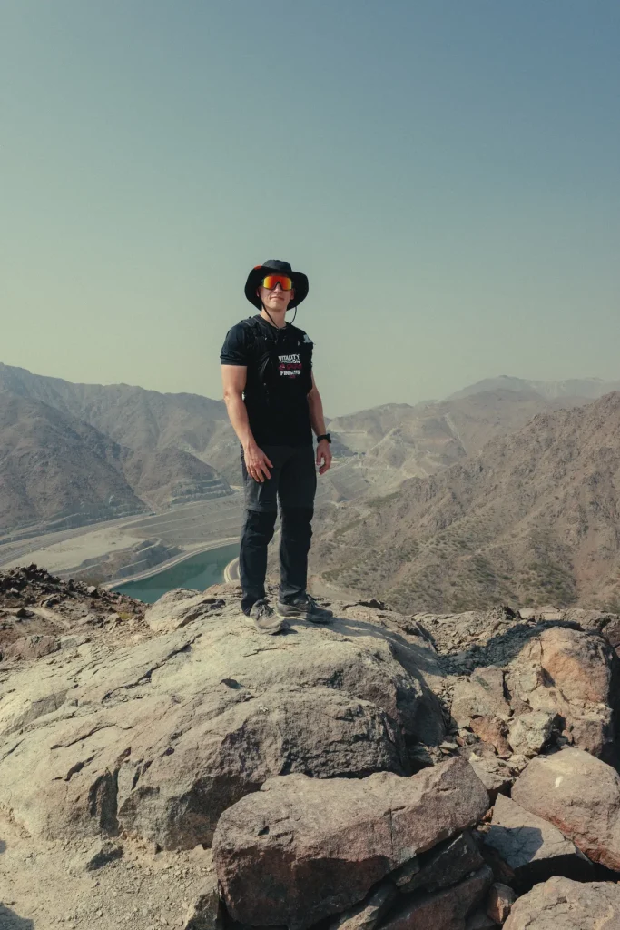 Hiker standing on a rocky summit overlooking the Hajar Mountains on Sharjah's east coast