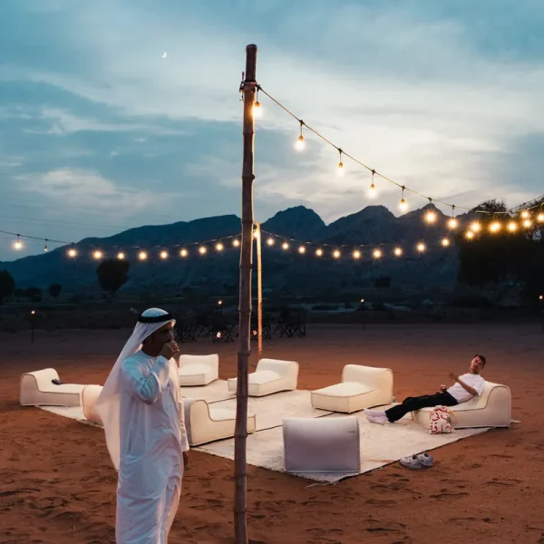 Desert camp with fairy lights and floor seating at dusk in Mleiha, ready for dinner under the stars