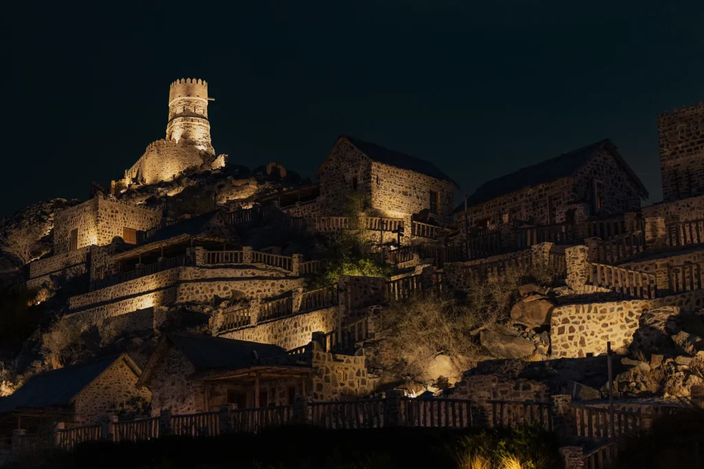 Najd Al Meqsar mountain village hotel and watchtower lit up at night near Khorfakkan