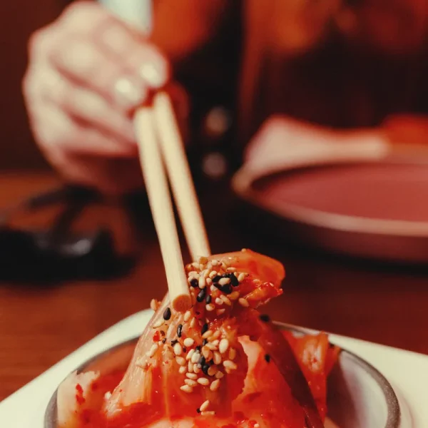 Picking up kimchi with chopsticks at Nomani, The Chedi Al Bait