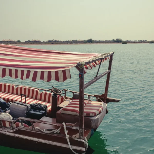 Traditional boat with a striped canopy that takes guests to Kingfisher Retreat in Kalba